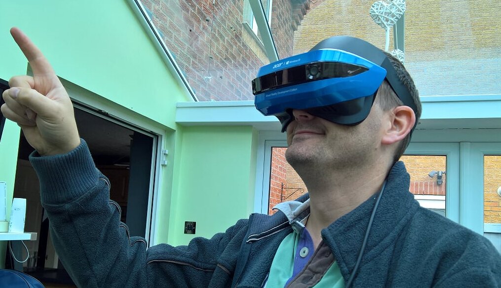 Simon wearing the blue Acer headset and pointing upwards